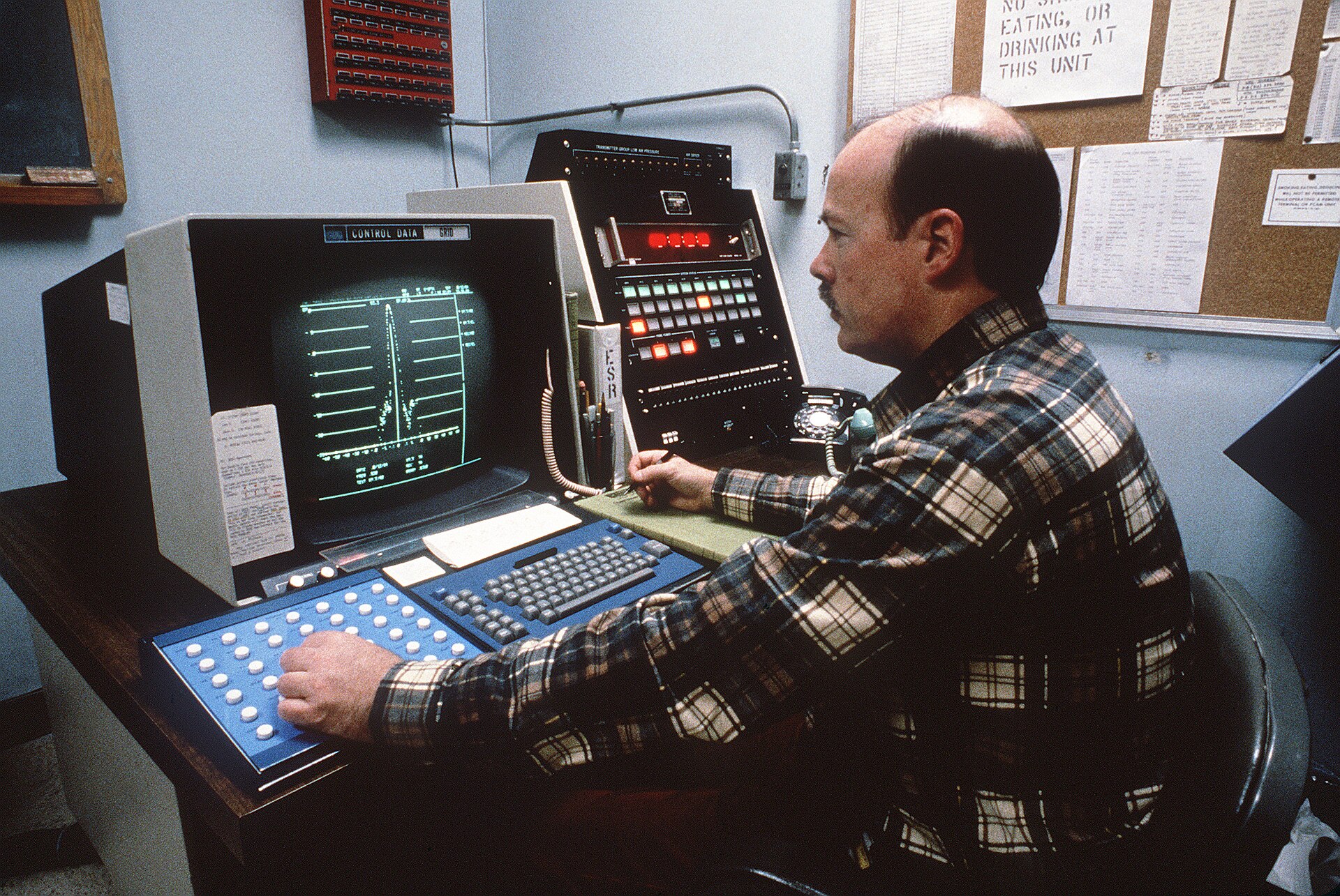 A control-room console with banks of status screens